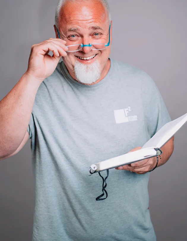 Franz Feldwebel mit Brille und Unterlagen in der Hand